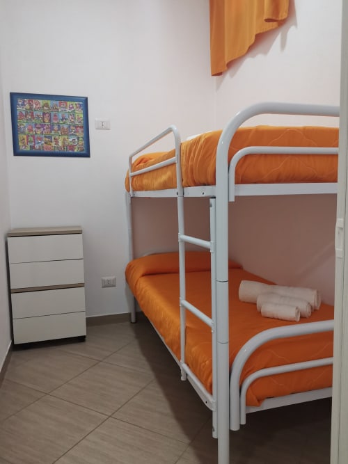 Twin bunk beds with orange bedding in Casa Vacanze Del Golfo apartment, Castellammare del Golfo