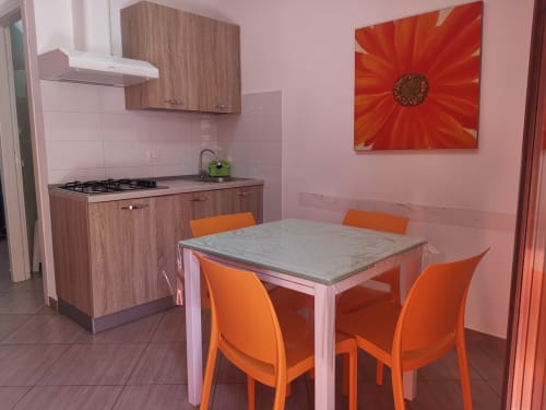 Modern kitchen-dining area in Apartment Orange at Casa Vacanze Del Golfo, with orange chairs and a marble table