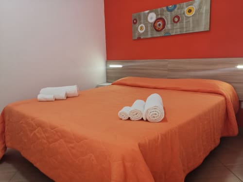 Orange bedroom with white rolled towels at Casa Vacanze Del Golfo, Castellammare del Golfo