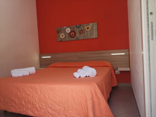 Modern orange bedroom at Casa Vacanze Del Golfo with rolled towels, contemporary headboard, and red wall art in Castellammare