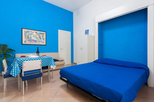 Camera luminosa con pareti blu a Casa Vacanze Del Golfo a Castellammare del Golfo, arredata con letto, zona living e mobili moderni