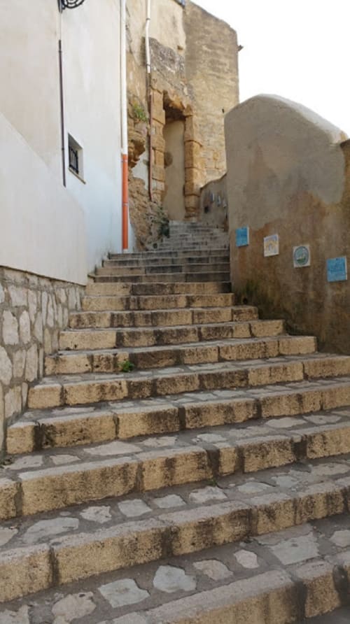 Stone stairway in Castellammare del Golfo leading to historic whitewashed buildings with terracotta architecture