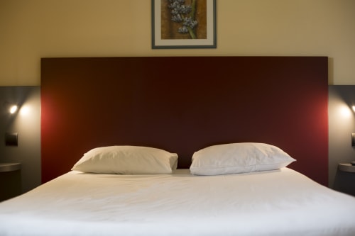 Chambre moderne de l'hôtel Mape à Dampierre-en-Burly avec literie blanche, tête de lit bordeaux et éclairage ambiant