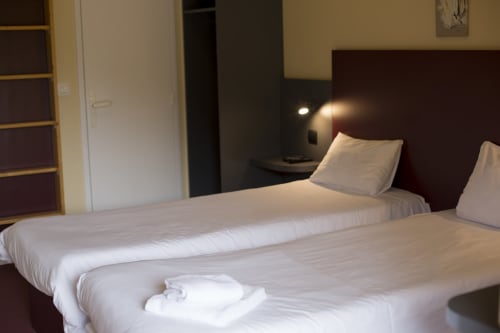 Chambre twin de l'hôtel Mape avec literie blanche, tête de lit sombre, lampes de chevet et vue sur le jardin à Dampierre en Burly