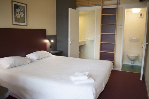 Chambre moderne à l'hôtel Mape à Dampierre en Burly avec lit queen-size, tête de lit couleur bordeaux, salle de bain attenante et jardin