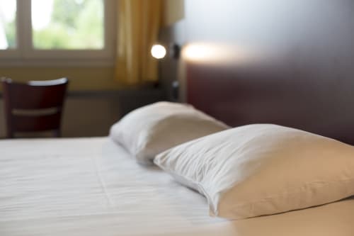 Chambre du Mape Hotel avec oreillers blancs, vue sur le jardin et équipements modernes à Dampierre-en-Burly