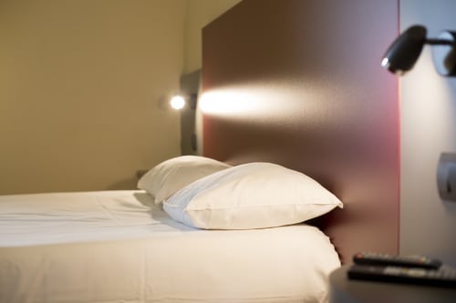 Oreillers blancs impeccables sur le lit de l'hôtel Mape à Dampierre en Burly avec éclairage moderne et espace de travail