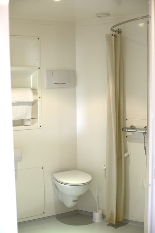 Salle de bains moderne à l'hôtel Mape avec toilettes, douche et rideau beige dans une chambre accessible