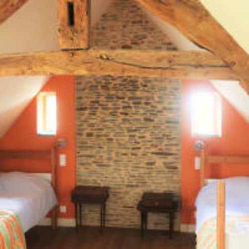 Chambre rustique à La Vieille Foulonnière à Pontorson avec poutres apparentes, mur en brique et lits jumeaux