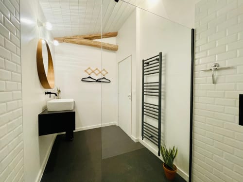 Modern bathroom at Maison Monsieur Léger with white subway tiles, black vanity, wooden mirror, and heated towel rack in
