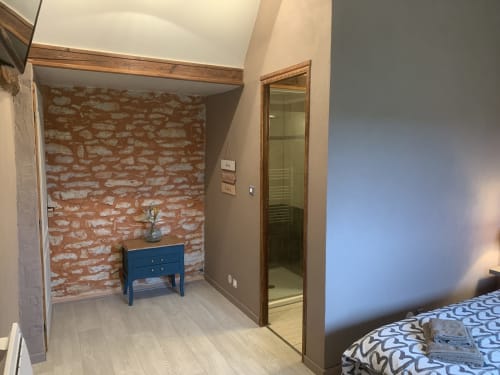 Bohème-Zimmer im La Maison de la Colline B&B in Vers, Frankreich, mit sichtbarem Ziegelwerk, blauem Sideboard und Holzbalken