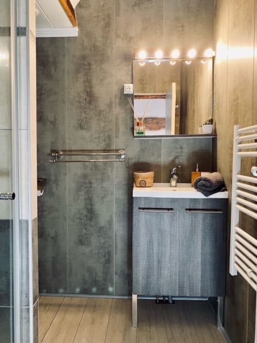 Modernes Badezimmer im La Maison de la Colline mit grauer Fliesendusche, Waschtisch, beleuchtetem Spiegel und weißem Handtuchhalter