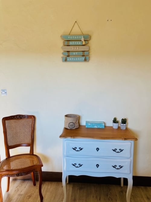 Gemütliches Zimmer im La Maison de la Colline B&B mit hellblauer Kommode, Holzstuhl und maritimer Wanddeko in Vers, Frankreich