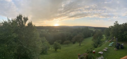 Panoramablick auf den Garten des Cottage La Maison de la Colline in Vers, Frankreich bei Sonnenuntergang mit grünem Hügelland