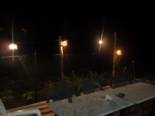 Terrasse nocturne de la chambre d'hôtes Caribgites à Sainte-Anne avec fauteuils de patio illuminés et luminaires brillants surplombant l'obscurité
