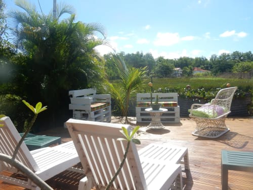 Terrasse de la chambre d'hôte Caribgites à Sainte-Anne avec transats blancs, palmiers et vue sur la campagne