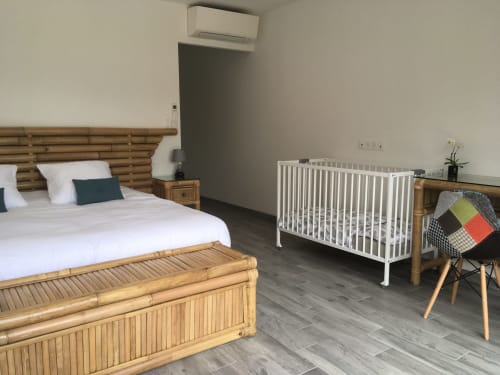 Chambre moderne au Domaine Des Bois Argentés avec lit queen-size, berceau blanc, mobilier en bois et vue sur le jardin