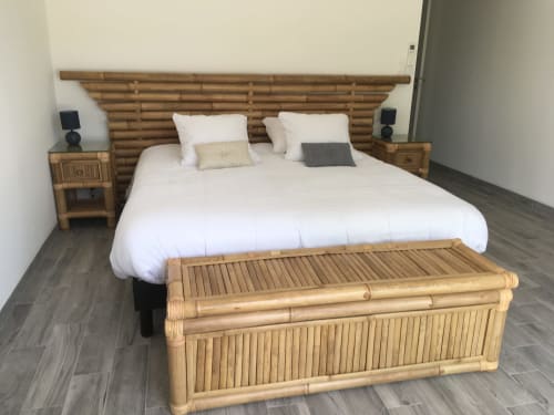 Chambre bambou aux Domaines des Bois Argentés avec literie blanche, tête de lit en bois, tables de nuit et banquette au pied du lit