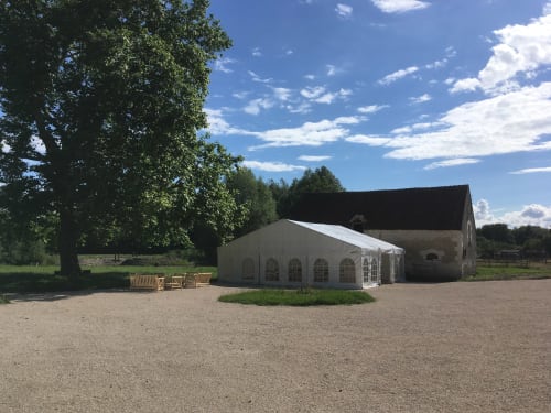 Chapiteau blanc sur le domaine des Bois Argentés près d'un bâtiment en pierre rustique sous un ciel bleu à Pruniers-en-Sologne