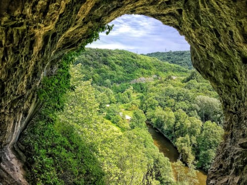 Vue à travers un ancien tunnel de pierre sur une vallée verdoyante et une rivière près du Moulin des Ramiers, Crupet Belgique