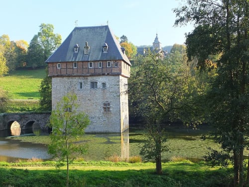 Tour en pierre historique avec toit mansardé au bord de la rivière, hôtel Le Moulin Des Ramiers à Crupet, Belgique