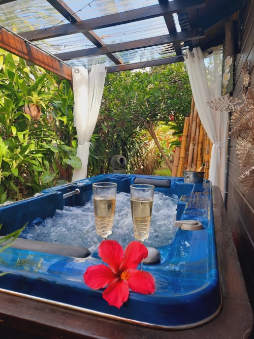 Blue hot tub with tropical flowers and wine glasses at Gites Kaladja in Port-Louis, Guadeloupe