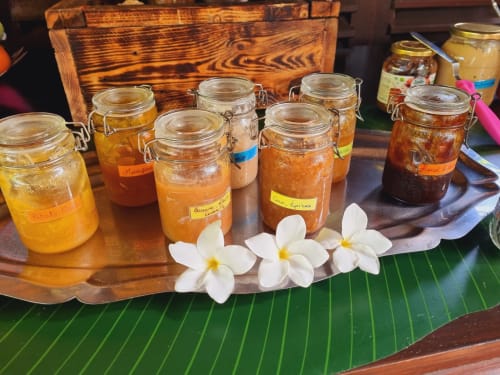 Homemade preserves and jams in jars displayed at Gites Kaladja, Port-Louis, Guadeloupe, with white flowers and wooden