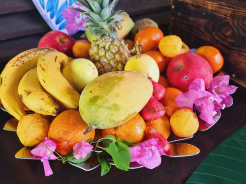 Tropical fruit display with bananas, mango, pineapple, and colorful flowers at Gites Kaladja in Port-Louis, Guadeloupe