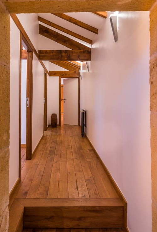 Couloir contemporain aux poutres en bois apparent, murs blancs et parquet au gîte Vue Sur Gindou à Gindou, France