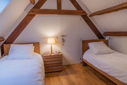 Chambre douillette sous les combles du gîte Vue Sur Gindou à Gindou avec lits jumeaux, poutres en bois et éclairage chaleureux