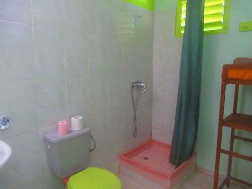 Salle de bains du gîte Caribgites à Sainte-Anne avec douche, toilettes et accents vert vif et rouge