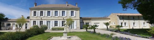 Le Manoir Lacustre B&B in Queyrac mit cremefarbener Steinfassade, gepflegten Gärten und Palmen