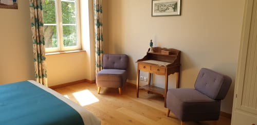 Chambre lumineuse au Château de Grandmont B&B à Blacé avec mobilier en bois, vue sur jardin et chaises vintage