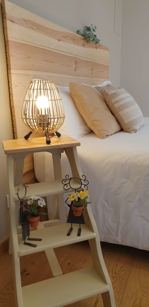 Table de nuit de la chambre du Château de Grandmont avec lampe en bois, fleurs en pot et oreillers