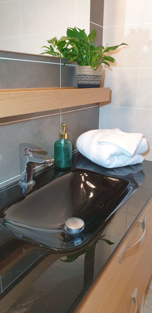 Lavabo moderne du gîte Château de Grandmont à Blacé : vasque noire, robinetterie chromée, serviettes blanches et plante