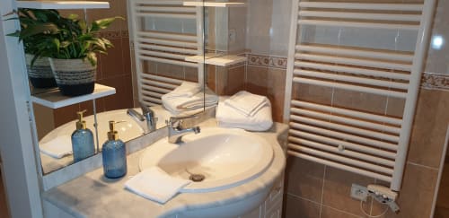 Salle de bain moderne au Château de Grandmont B&B à Blacé avec lavabo courbe, stores rayés et accessoires de toilette