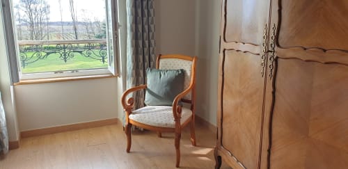 Chambre élégante au Château de Grandmont avec vue sur jardin, chaise en bois, armoire et parquet