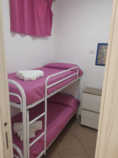 Bunk bed with pink bedding and white towels in apartment at Casa Vacanze Del Golfo, Castellammare del Golfo