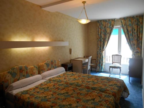 Chambre spacieuse à L'Abri Des Vents à Saint-Jean-le-Thomas avec literie motifs, bureau, accès balcon et ambiance chaleureuse