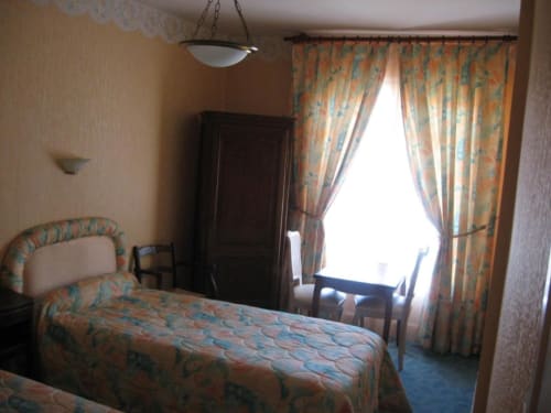 Chambre d'hôtel à L'Abri Des Vents avec lit à motifs, rideaux et accès au balcon à Saint-Jean-le-Thomas