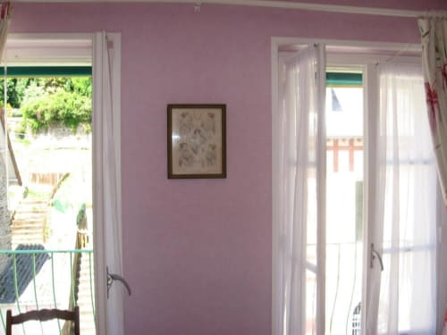 Chambre rose avec portes blanches ouvrant sur balcon à L'Abri Des Vents, Saint-Jean-le-Thomas