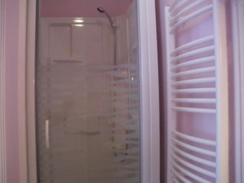 Salle de bain moderne avec douche vitrée et sèche-serviettes blanc chauffant à L'Abri Des Vents
