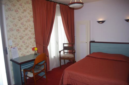 Chambre douillette à l'A L'Abri Des Vents à Saint-Jean-le-Thomas avec literie rouge, papier peint fleuri, bureau et rideaux rouges
