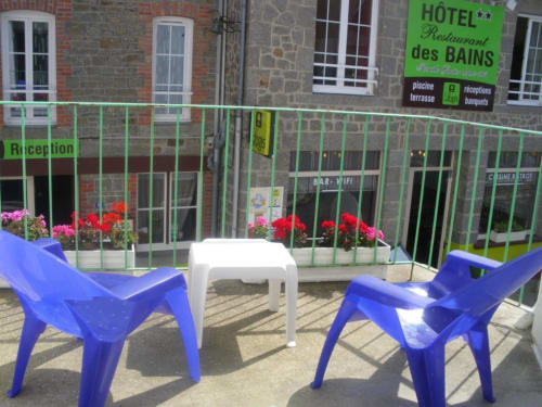 Terrasse de l'Hôtel des Bains à Saint-Jean-le-Thomas avec chaises bleues, table blanche et fleurs roses