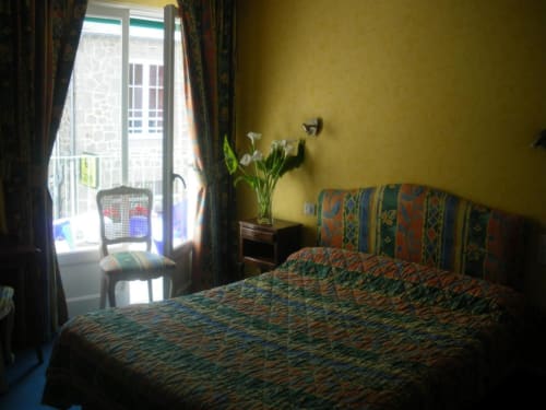 Chambre lumineuse aux motifs colorés, murs jaunes, portes-fenêtres donnant sur vue mer et fleurs à L'Abri Des Vents