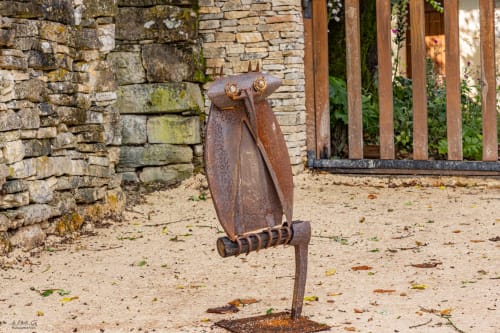 Rustic metal owl sculpture in courtyard at Vue Sur Gindou, a French B&B in Gindou with stone walls