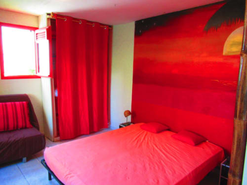 Chambre rouge éclatante à la Caribgites BnB à Sainte-Anne avec lit, rideaux et mobilier moderne
