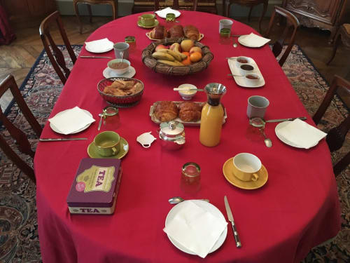 Elegant breakfast table at Le Fassardy B&B Châteauroux with red cloth, fresh fruit, pastries, tea and place settings