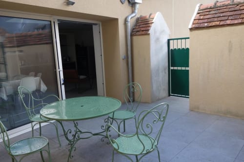Terrasse charmante du gîte Le Fassardy à Châteauroux avec mobilier en fer forgé vert et vue sur le jardin