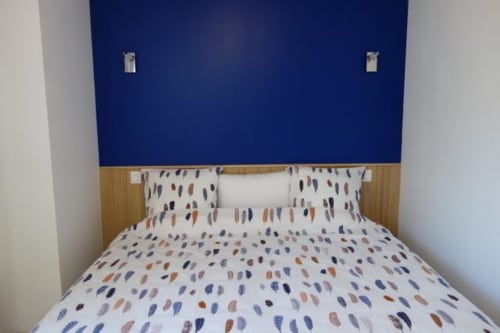 Chambre douillette au Gîte Le Fassardy à Châteauroux, avec literie à motifs, tête de lit en bois et mur d'accent bleu marine